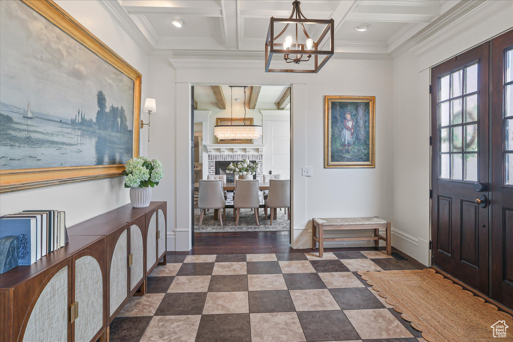 Entryway with a chandelier, coffered ceiling, baseboards, beam ceiling, and crown molding