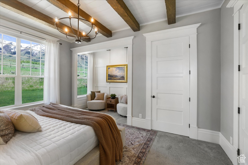 Carpeted bedroom with a chandelier, beamed ceiling, and baseboards