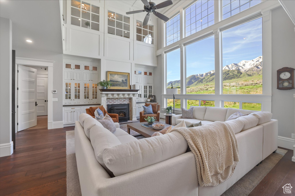 Living area featuring dark wood-type flooring, baseboards, a high ceiling, a ceiling fan, and a mountain view