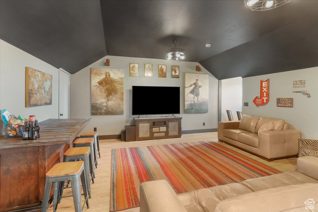 Living area with lofted ceiling, light wood finished floors, and baseboards