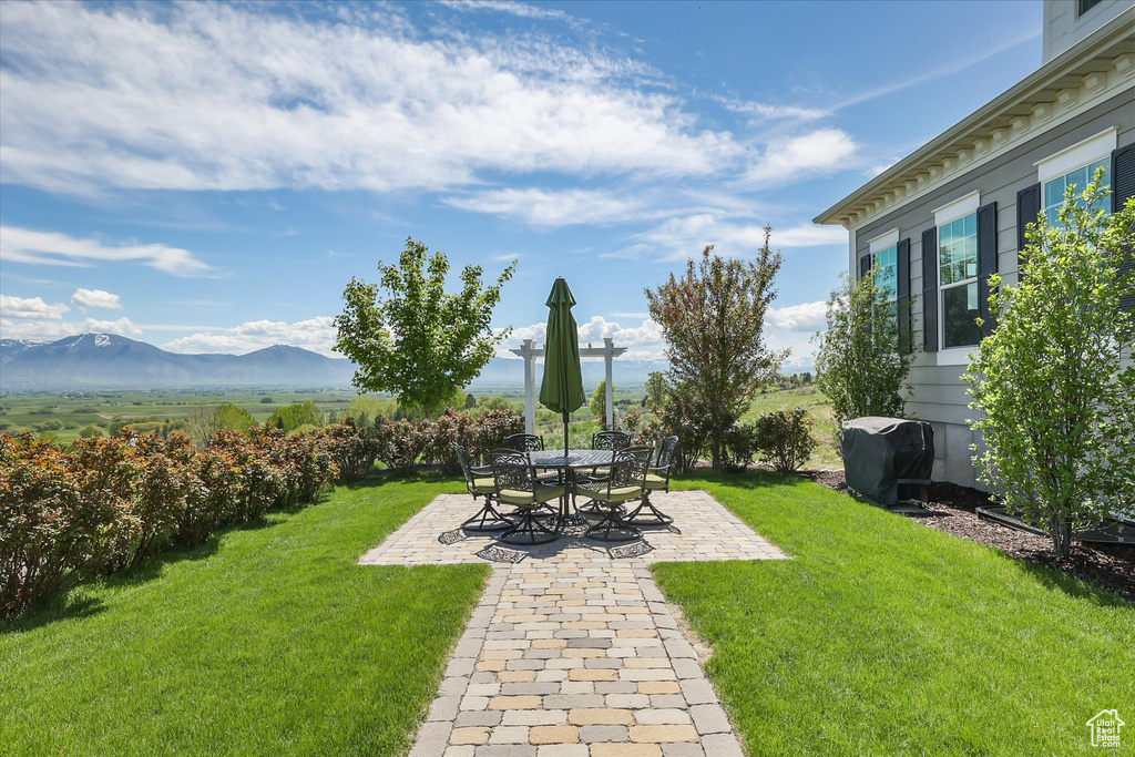 View of grassy yard with a patio and a mountain view