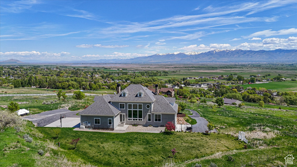 Back of property featuring a mountain view, entry steps, and a yard