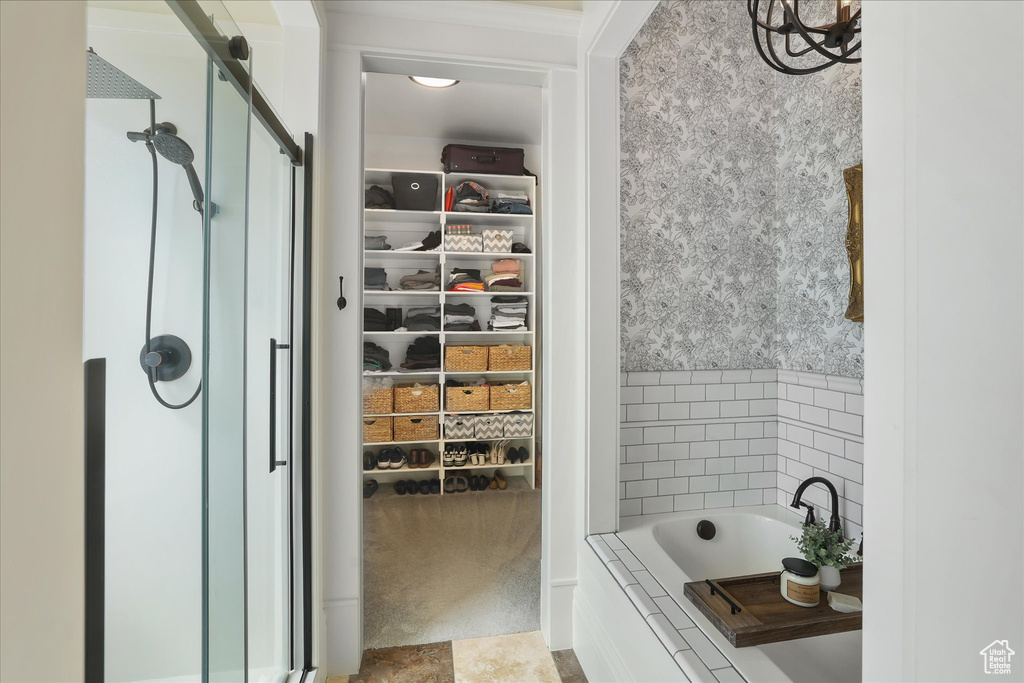 Full bath featuring a shower stall, a spacious closet, and tiled bath