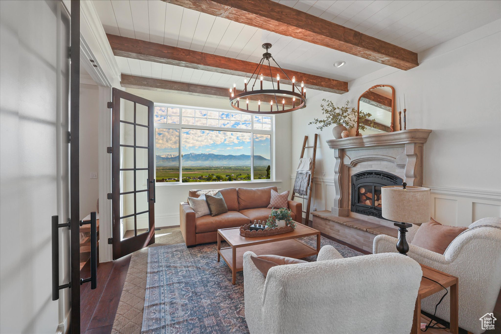 Living area with a chandelier, a glass covered fireplace, wood finished floors, beam ceiling, and wooden ceiling