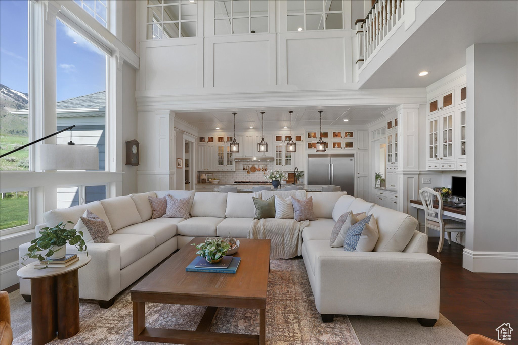 Living area with a high ceiling, an office area, wood finished floors, and recessed lighting