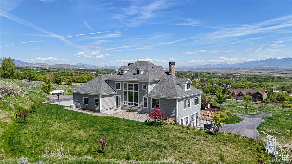 Back of property featuring a chimney, a mountain view, a yard, and a shingled roof