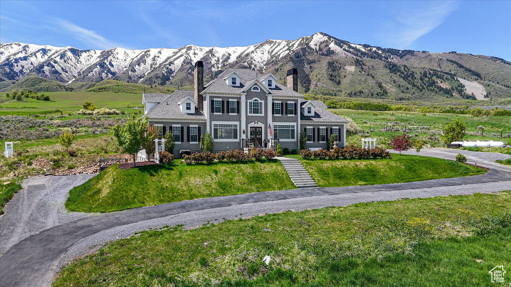 View of front of home with a chimney, a mountain view, and a front yard
