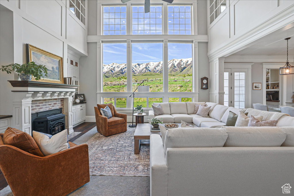 Living room featuring a towering ceiling, ceiling fan, dark wood finished floors, and crown molding