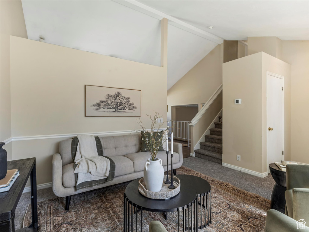 Carpeted living area with vaulted ceiling, stairway, and baseboards
