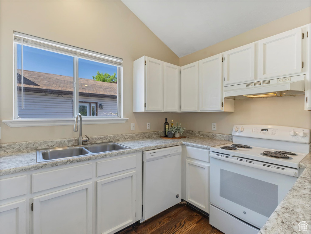 Kitchen featuring white appliances, under cabinet range hood, a sink, lofted ceiling, and white cabinetry