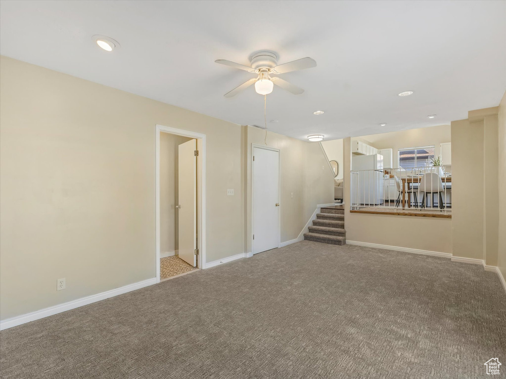 Unfurnished room with a ceiling fan, stairway, carpet floors, and baseboards