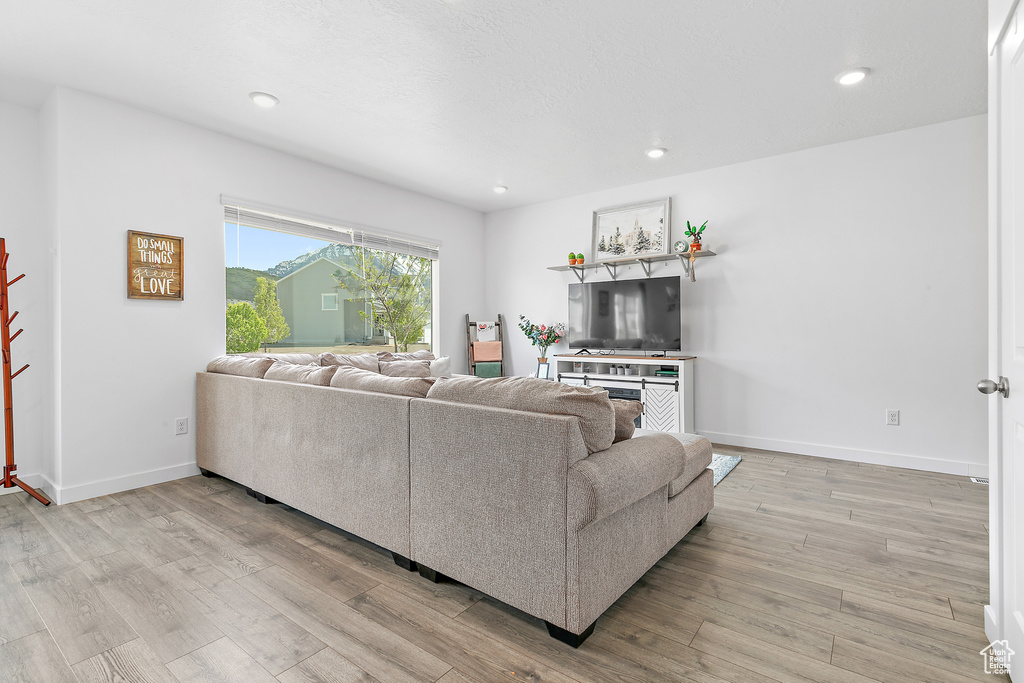 Living room with wood finished floors, recessed lighting, and baseboards