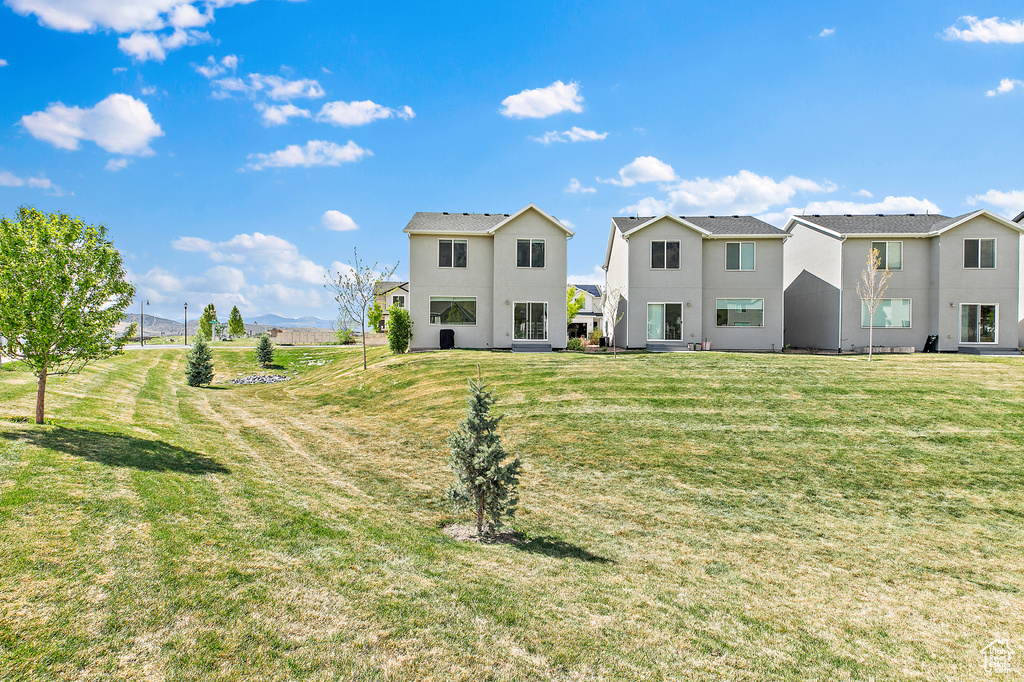 Rear view of house featuring stucco siding and a yard
