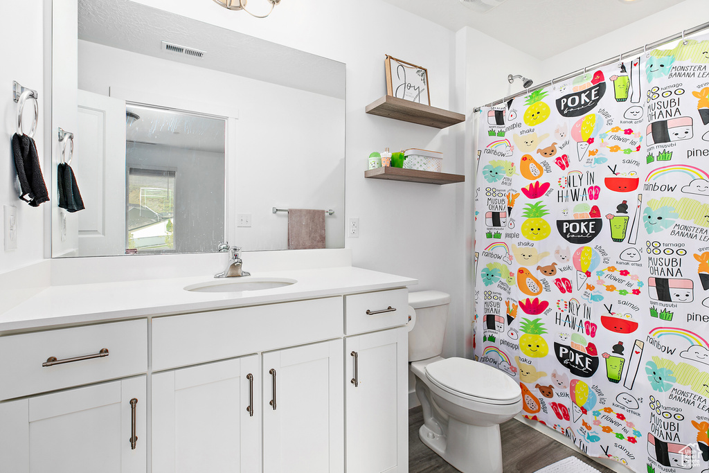 Full bath with toilet, vanity, wood finished floors, and a shower with shower curtain
