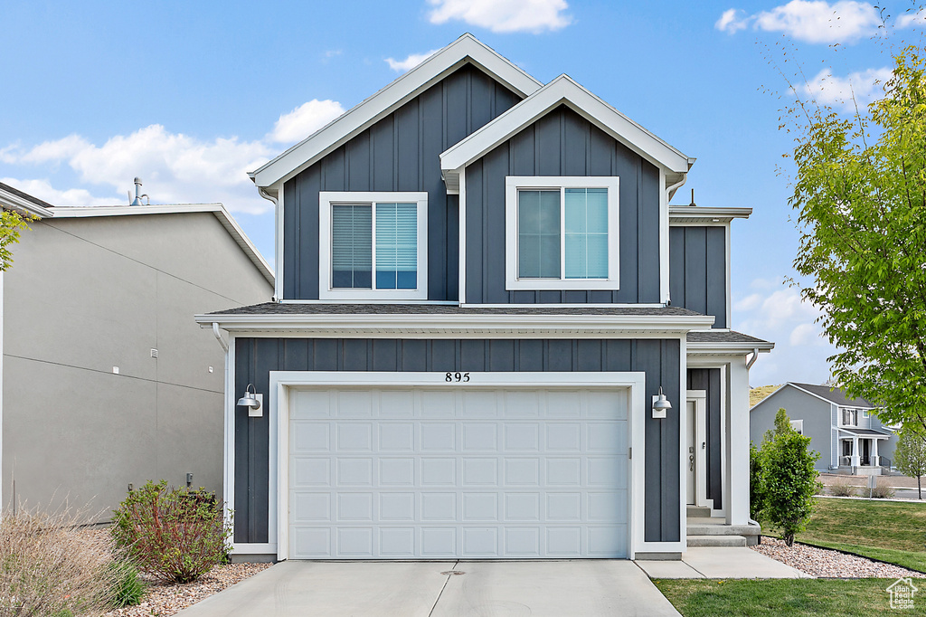 Traditional-style house featuring board and batten siding, concrete driveway, and an attached garage
