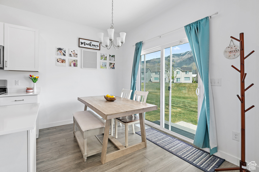 Dining space with a chandelier, light wood finished floors, baseboards, and a mountain view