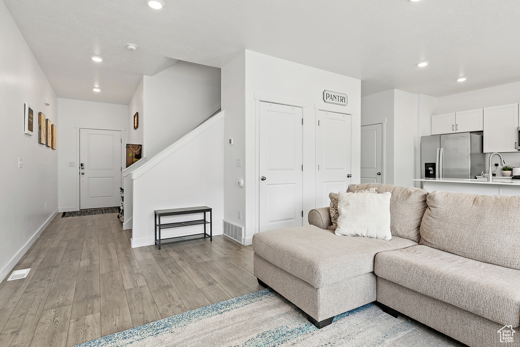 Living room with recessed lighting, light wood-type flooring, baseboards, and stairs