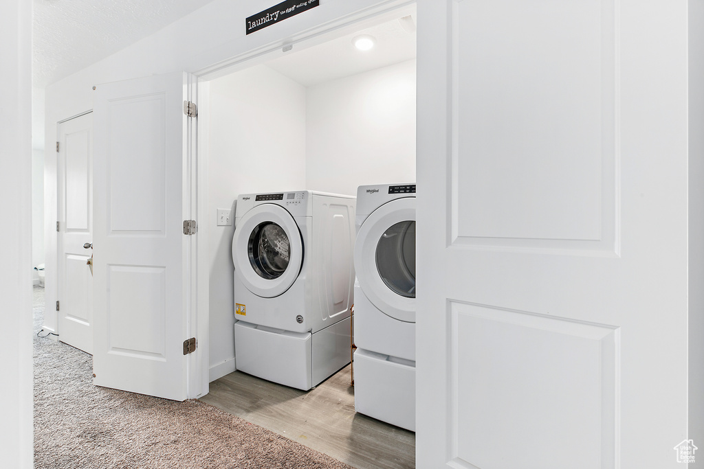 Laundry area featuring separate washer and dryer, light wood finished floors, and light carpet