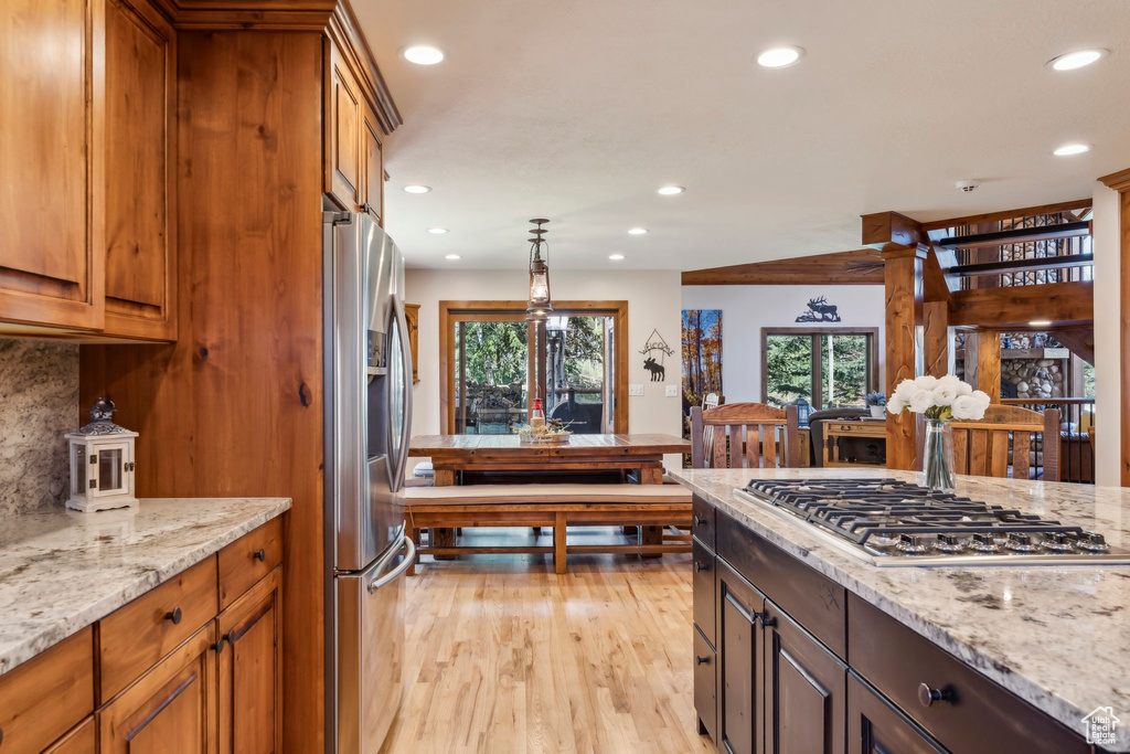 Kitchen with appliances with stainless steel finishes, recessed lighting, plenty of natural light, light wood-style floors, and light stone counters