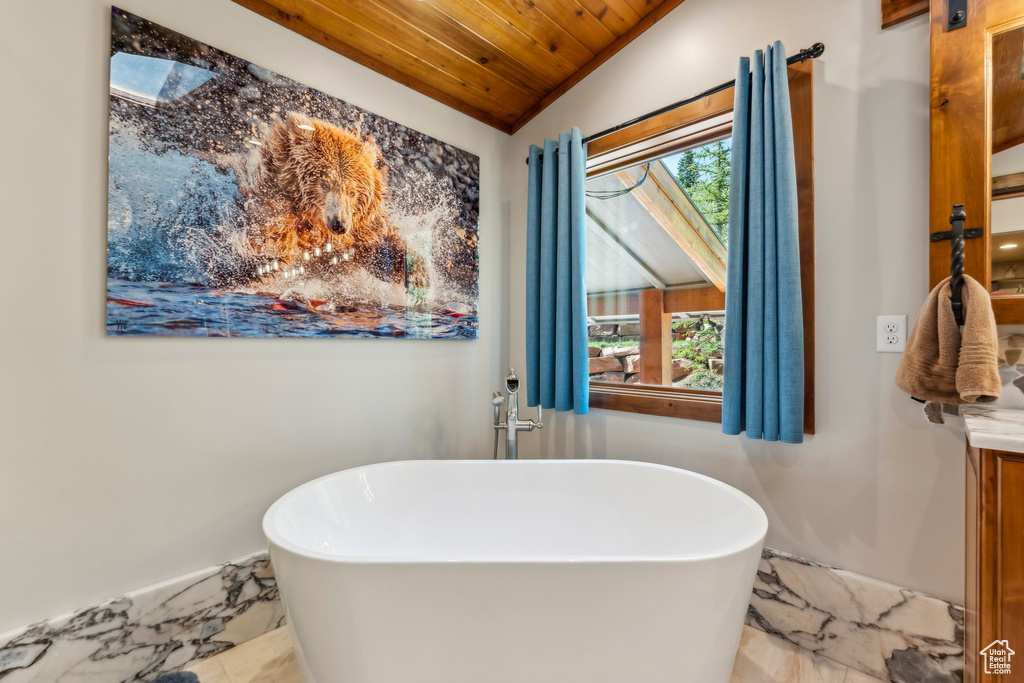 Bathroom featuring a freestanding tub, wood ceiling, marble look tiles, vanity, and lofted ceiling