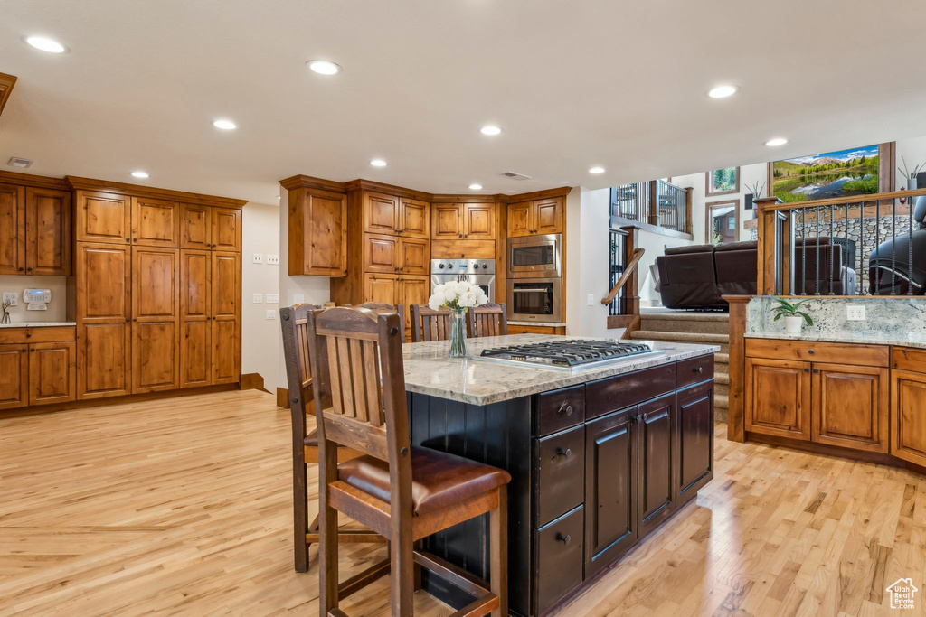 Kitchen featuring appliances with stainless steel finishes, light wood-style flooring, recessed lighting, and brown cabinetry