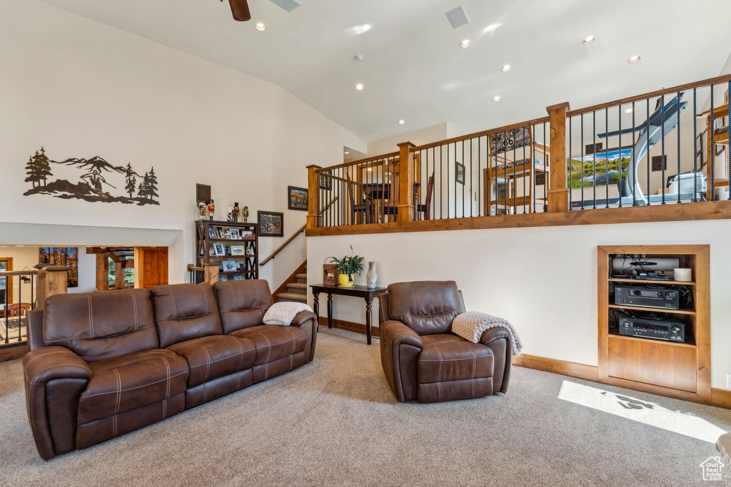 Living area with carpet, baseboards, high vaulted ceiling, stairway, and recessed lighting