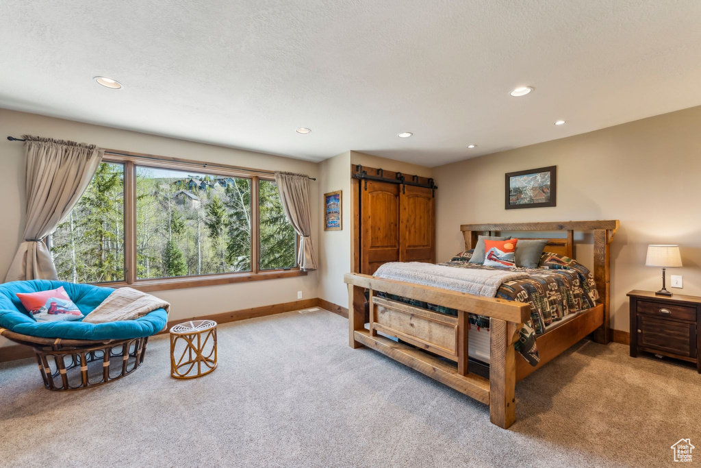 Bedroom featuring light colored carpet, a barn door, baseboards, and recessed lighting