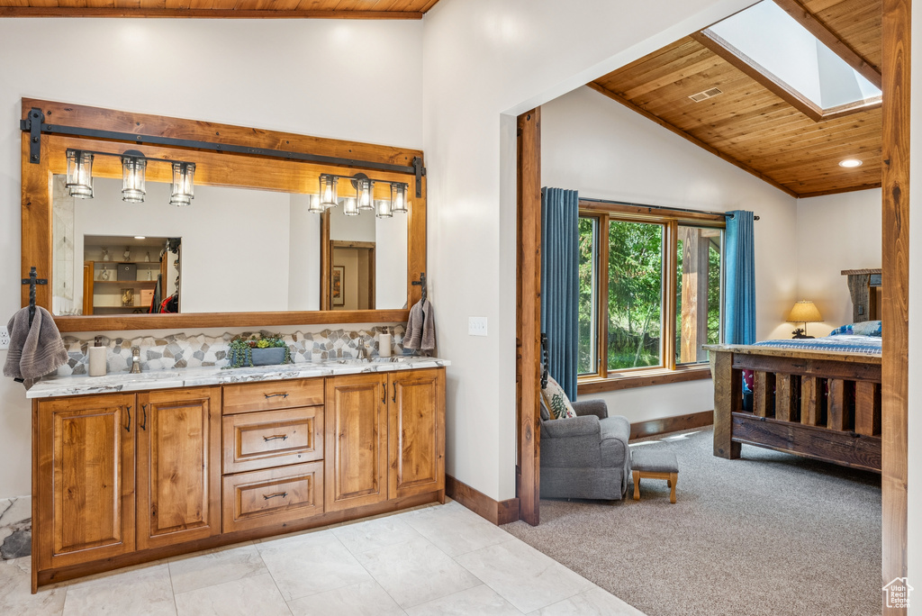 Full bath with wood ceiling, double vanity, a skylight, tasteful backsplash, and recessed lighting