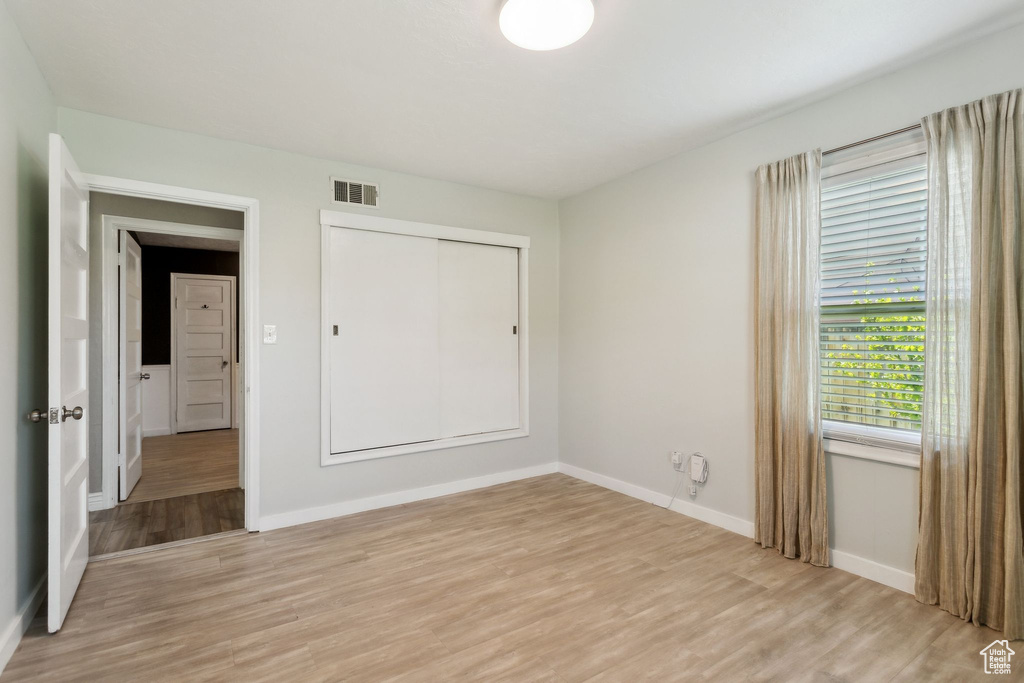 Unfurnished bedroom with light wood finished floors, baseboards, and a closet