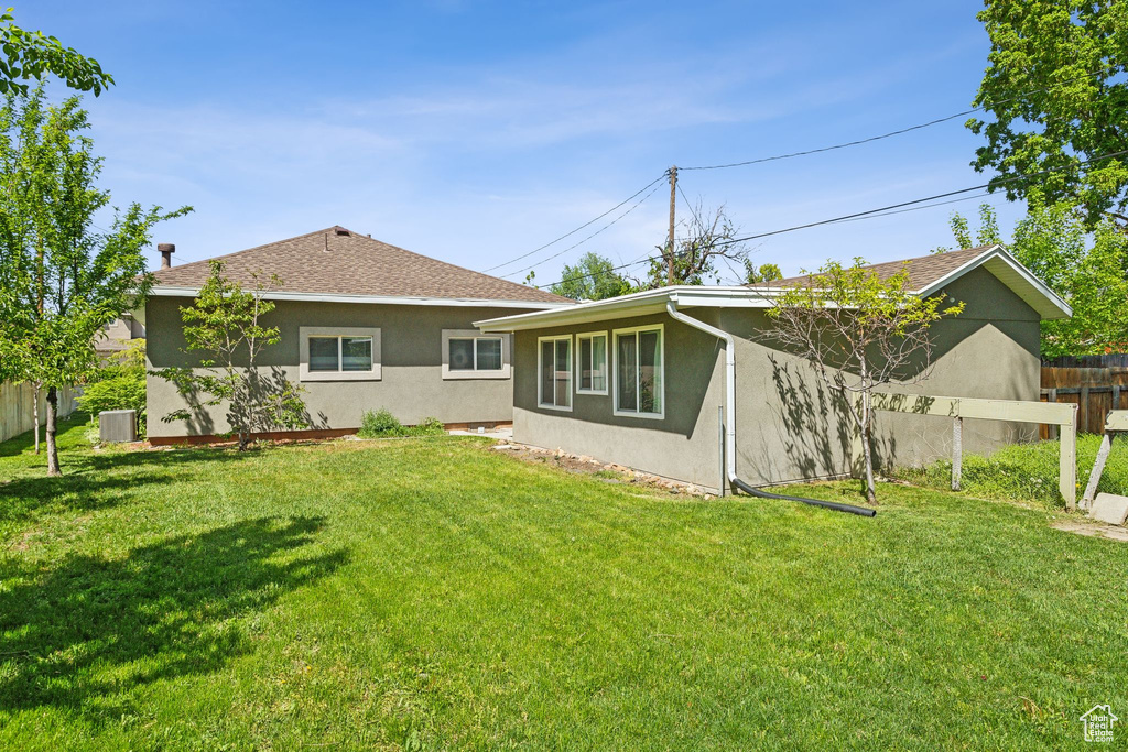 Back of property with stucco siding, central air condition unit, and roof with shingles