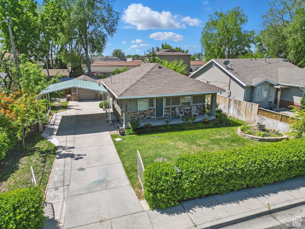 View of front of property featuring concrete driveway, a porch, roof with shingles, and a detached carport