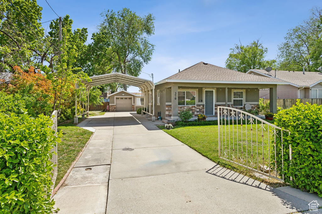 Bungalow-style house with an outdoor structure, a carport, a porch, a garage, and a shingled roof