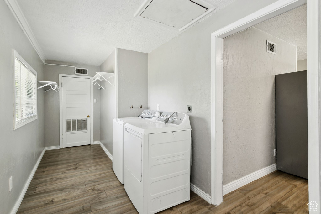 Laundry area featuring washing machine and dryer, wood finished floors, attic access, baseboards, and crown molding