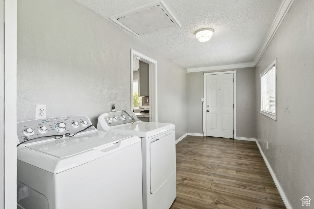 Washroom featuring separate washer and dryer, attic access, a textured ceiling, wood finished floors, and baseboards