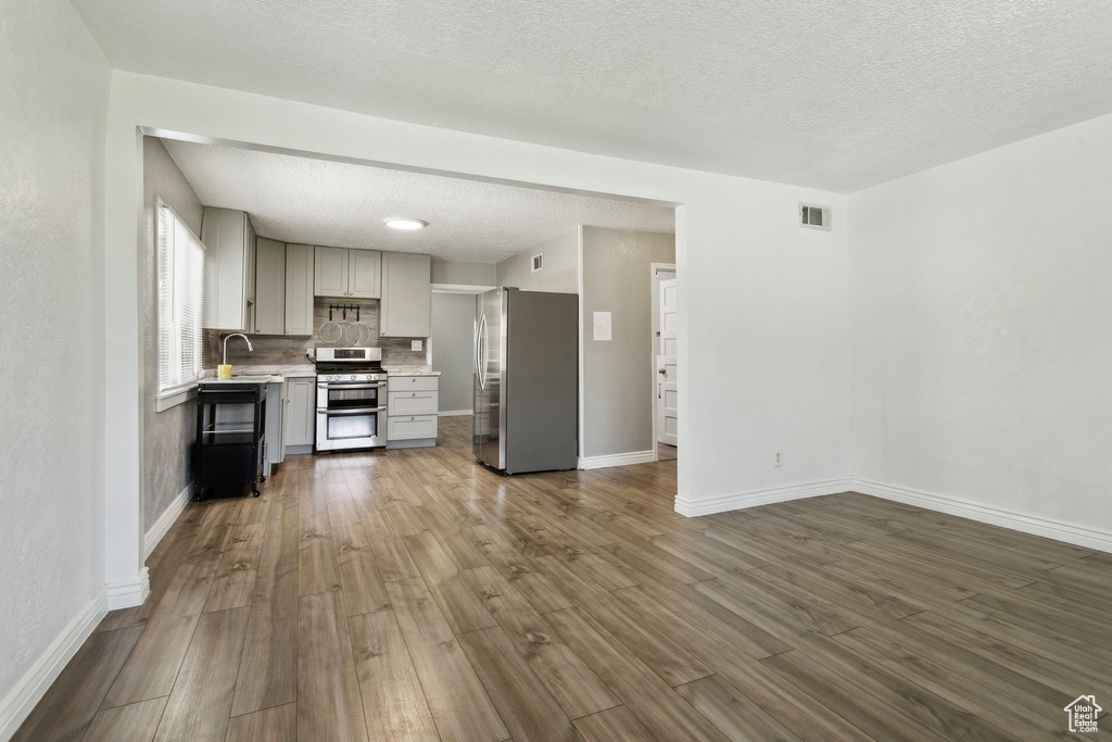 Kitchen with stainless steel appliances, gray cabinetry, light countertops, baseboards, and a textured ceiling