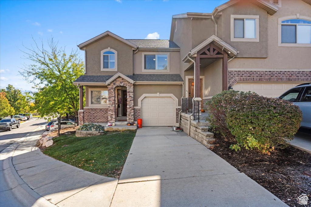 View of front of home featuring stucco siding, an attached garage, concrete driveway, and stone siding