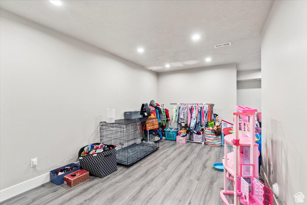 Recreation room with wood finished floors, recessed lighting, and baseboards