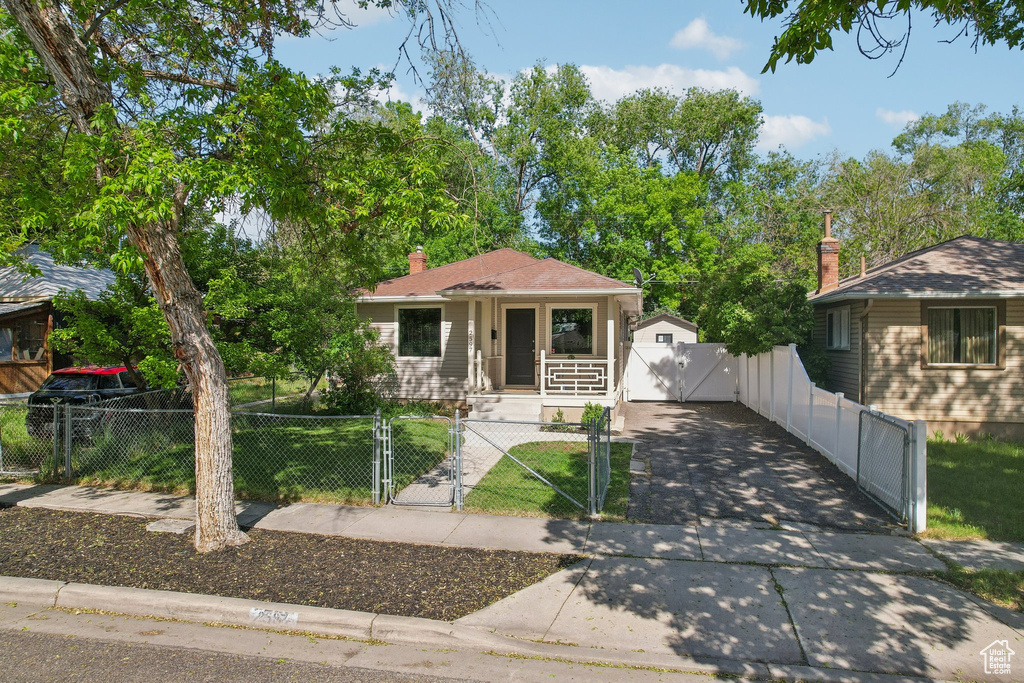 View of front of home featuring a gate, a porch, a fenced front yard, a chimney, and a garage