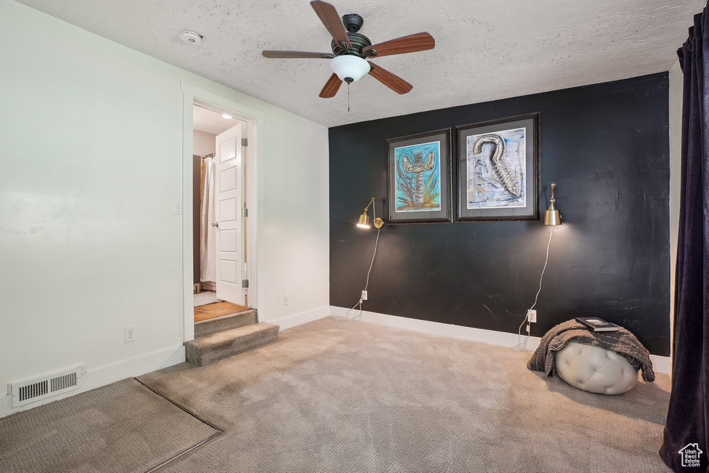 Spare room with carpet floors, ceiling fan, baseboards, and a textured ceiling