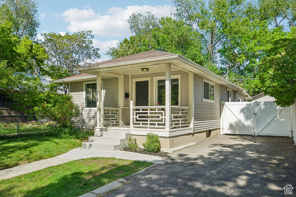 View of front facade with a porch, driveway, and a gate