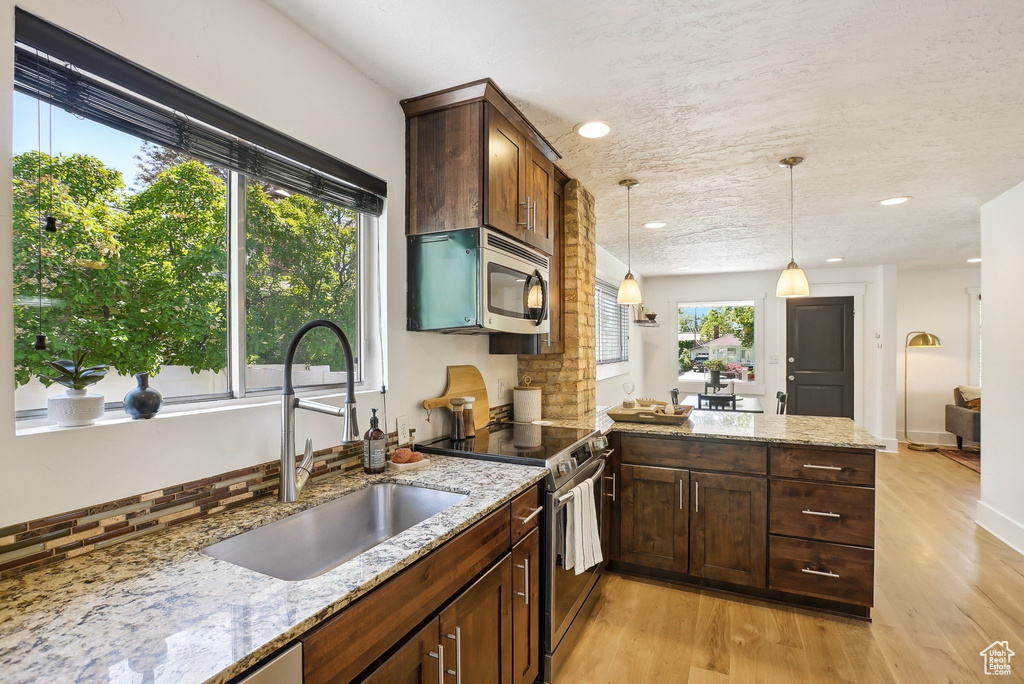 Kitchen with stainless steel appliances, a sink, light wood-style flooring, a peninsula, and recessed lighting