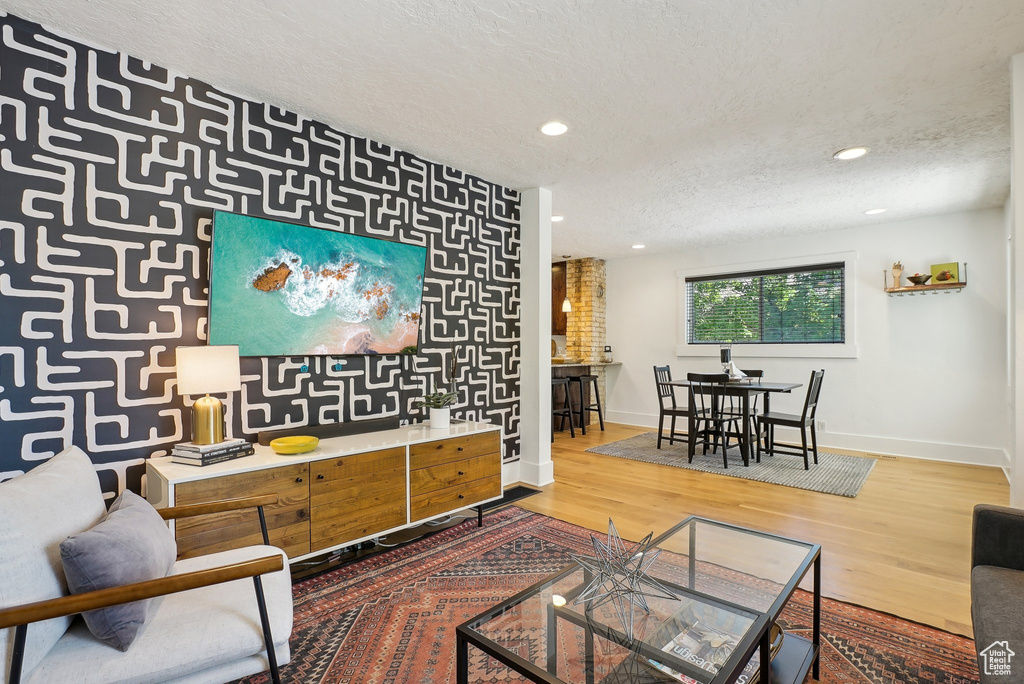 Living area with a textured ceiling, baseboards, wood finished floors, and recessed lighting