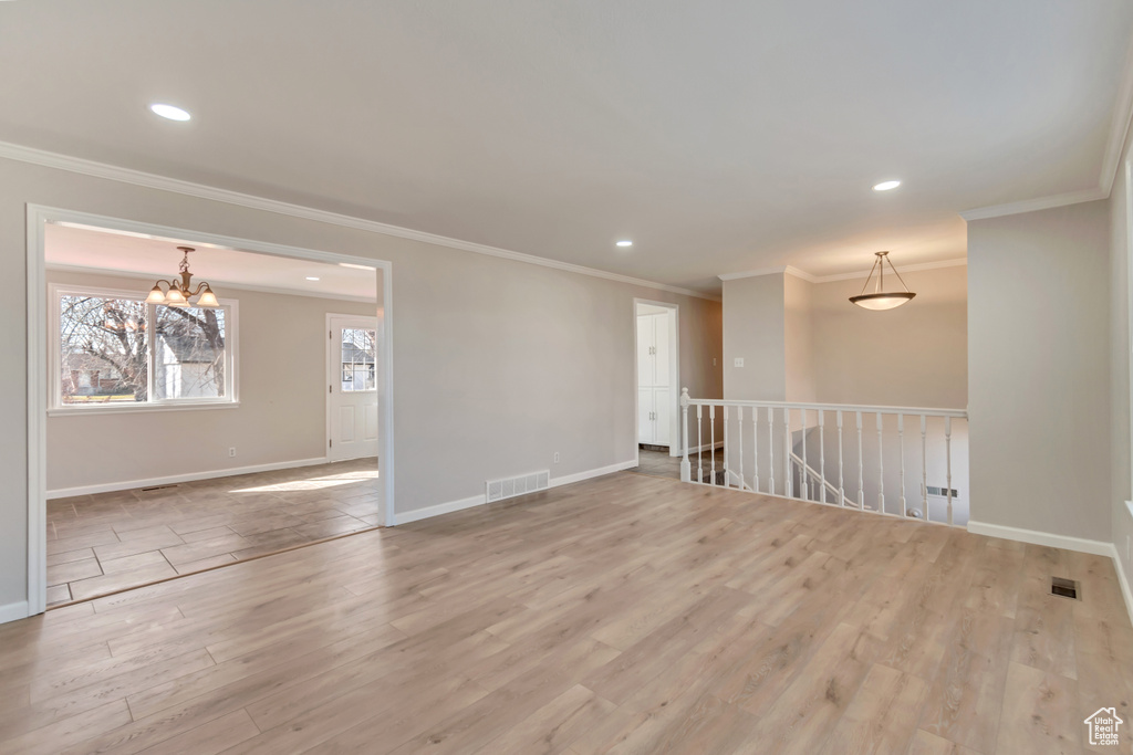 Unfurnished room featuring crown molding, light wood-type flooring, baseboards, a chandelier, and recessed lighting