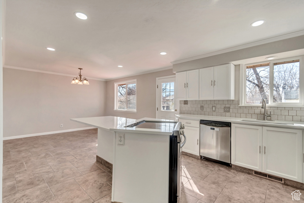 Kitchen featuring dishwasher, a sink, ornamental molding, a chandelier, and light countertops