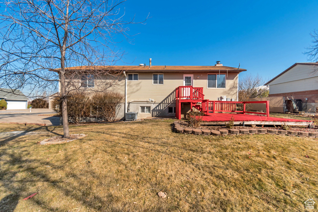 Back of house featuring a wooden deck, a lawn, and central AC unit