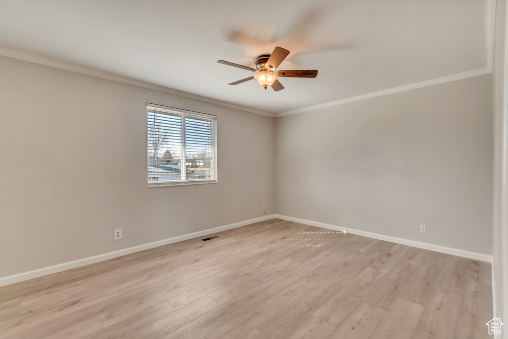 Empty room with crown molding, a ceiling fan, baseboards, and light wood-style flooring