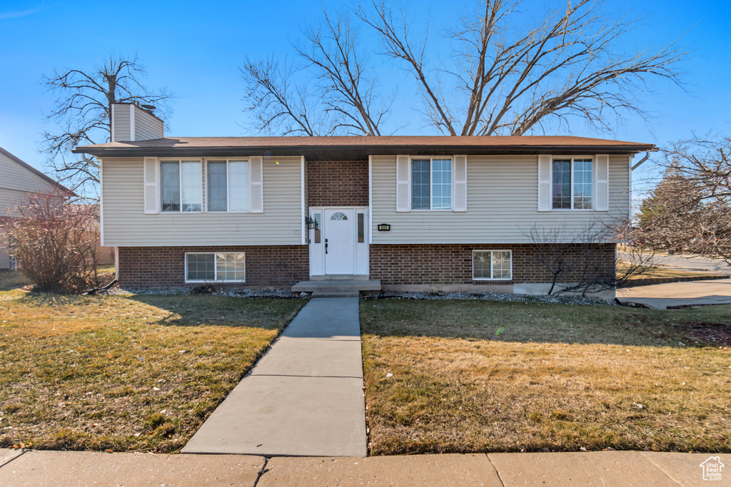 Bi-level home featuring a front yard, brick siding, and a chimney