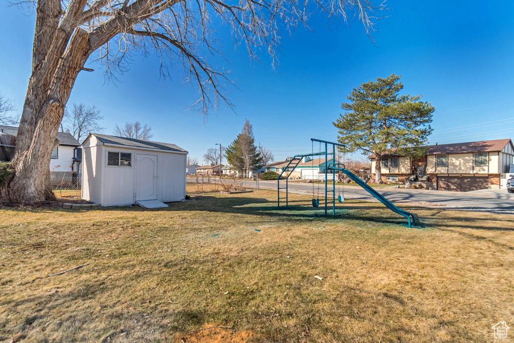 View of yard featuring a storage unit, a playground, and an outbuilding
