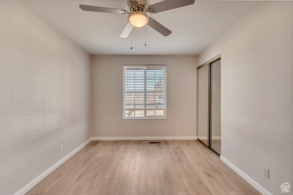 Unfurnished bedroom with light wood-type flooring, baseboards, a closet, and a ceiling fan