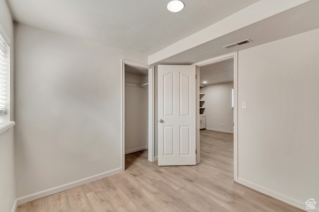 Unfurnished bedroom featuring baseboards, light wood-type flooring, and a closet